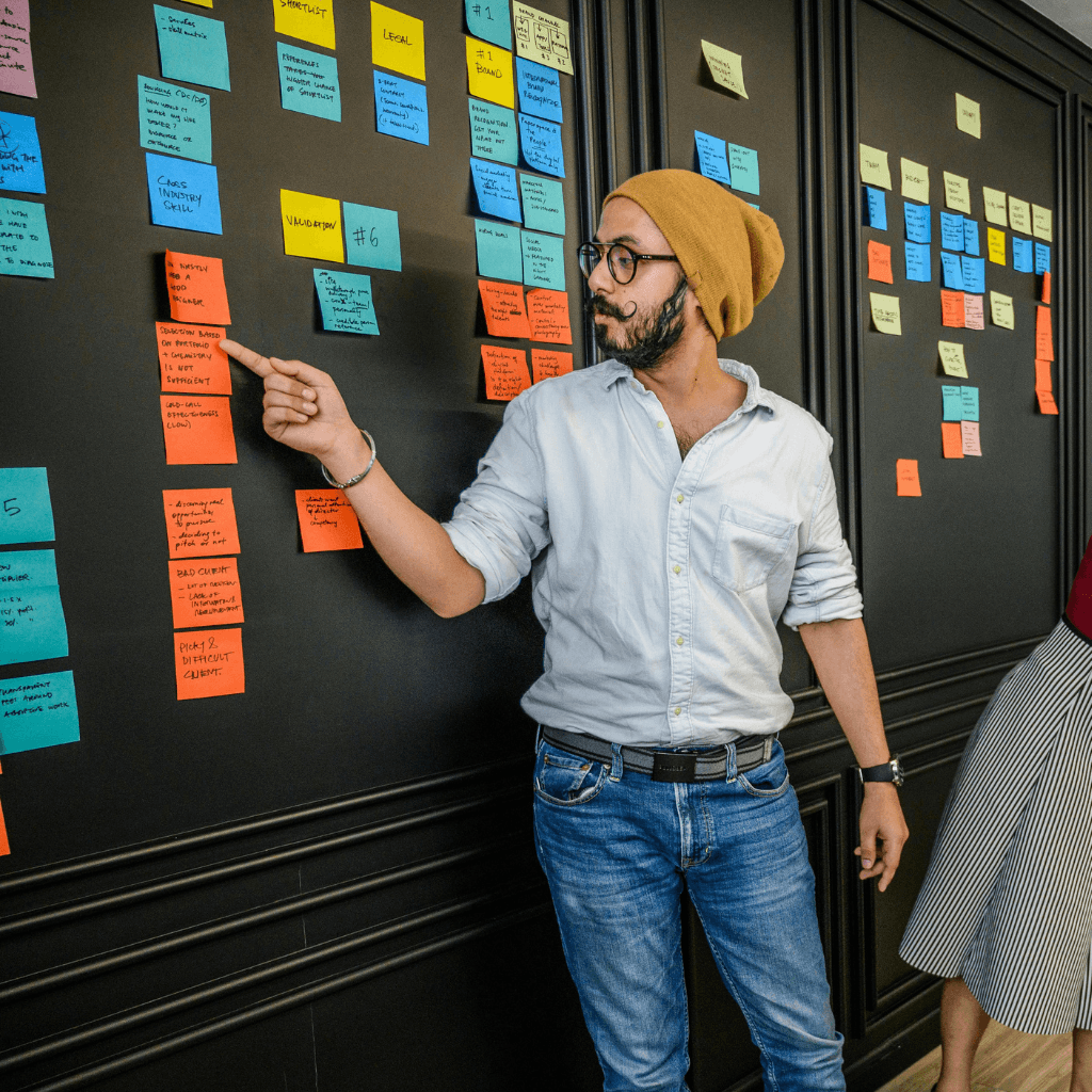 Un scrum master animant un atelier, tableau fond noir avec des post-it de couleurs