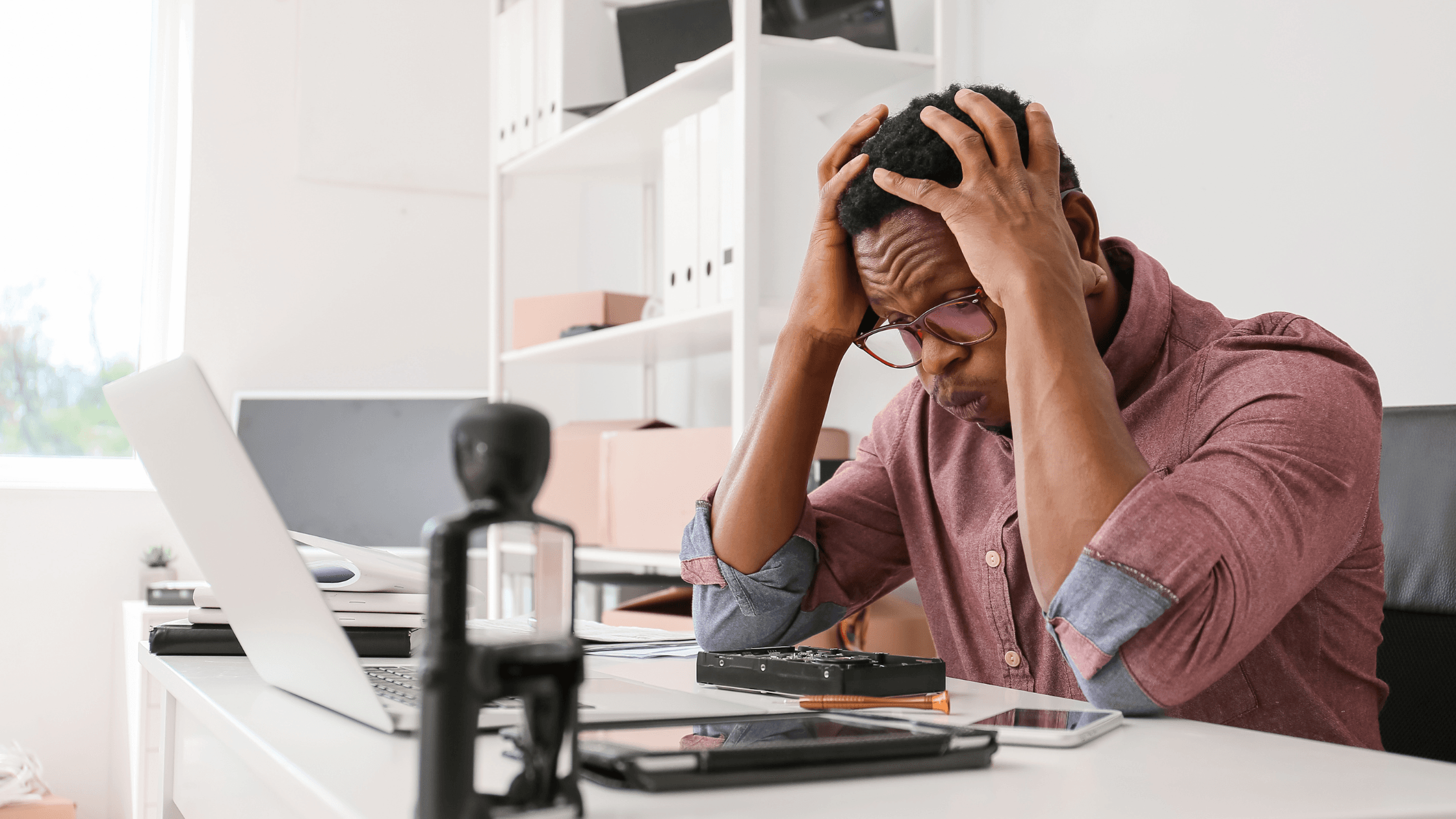 Un homme à son bureau qui se tient la tête devant son PC