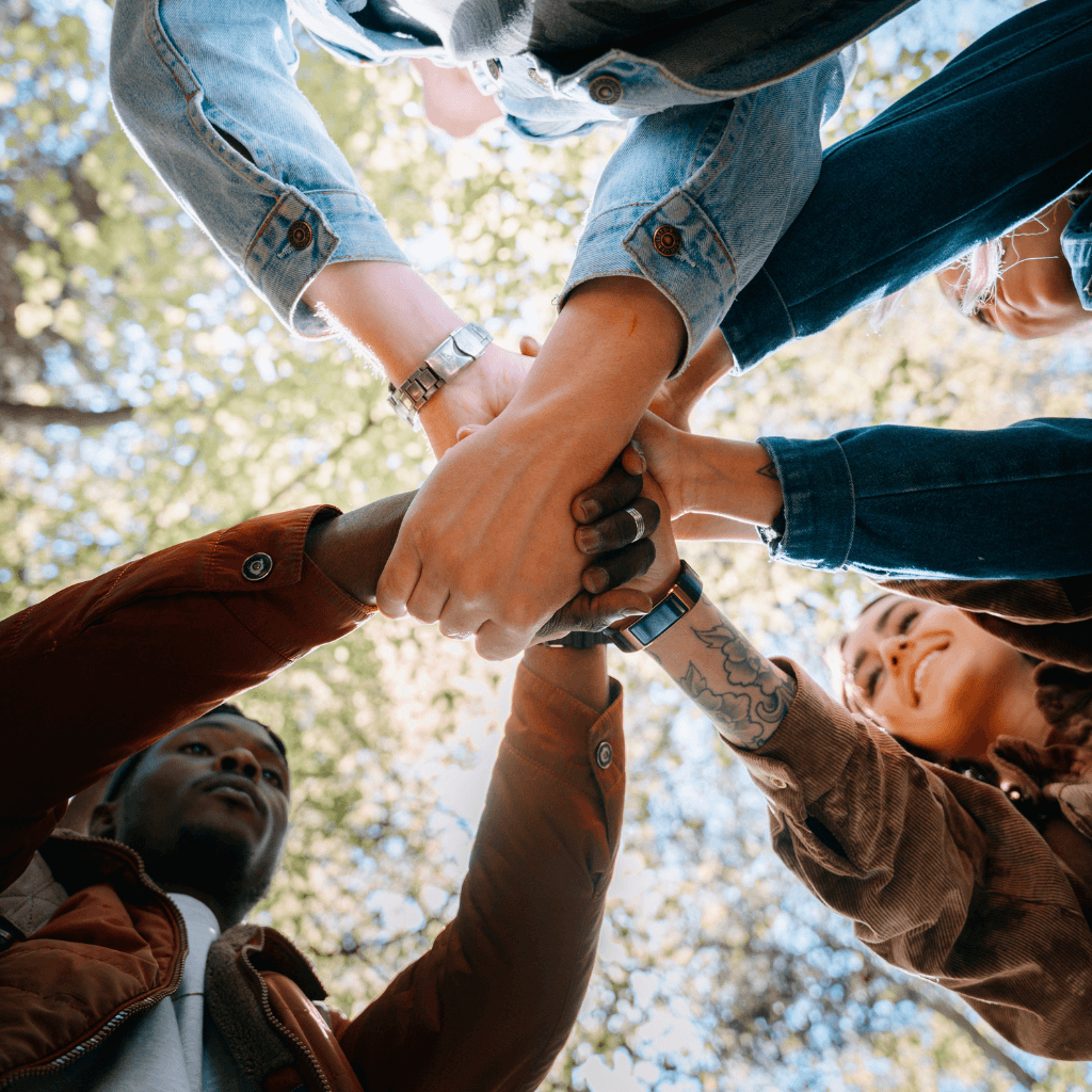 Équipe de développeurs collaborant et joignant les mains en cercle, symbole du travail d’équipe