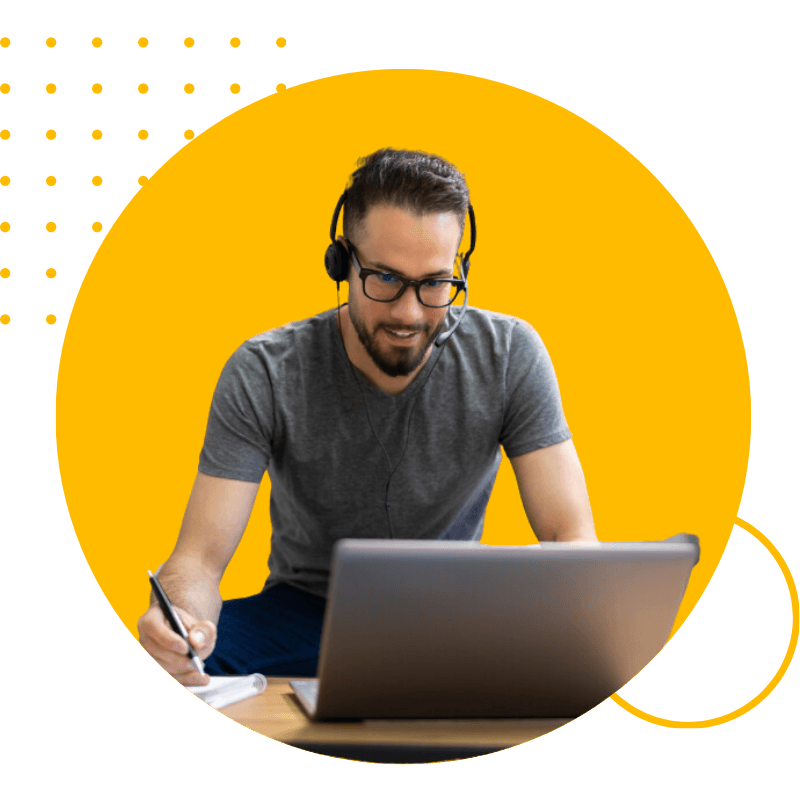 Homme devant son PC en train de prendre des notes